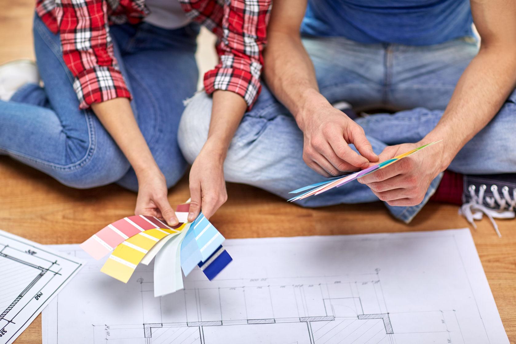 38817498 - design, repair, decoration and people concept - close up of couple with blueprint and color samples sitting on floor at home